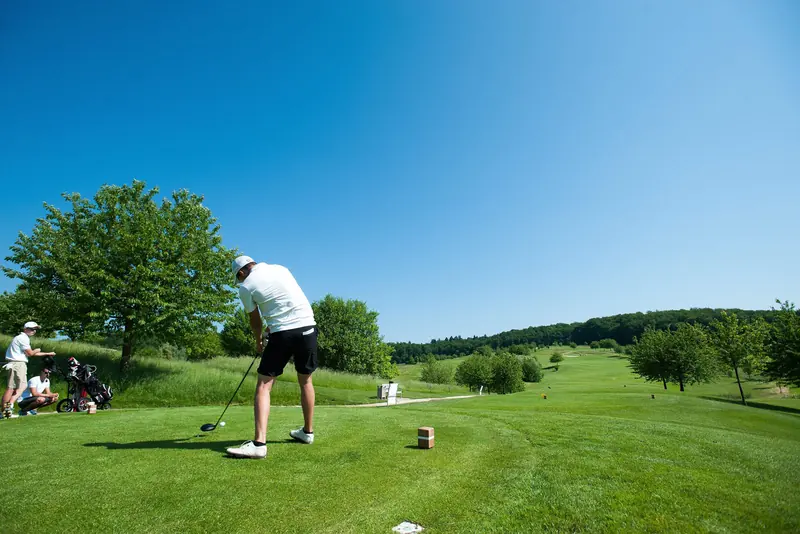 Golfer beim Abschlag auf einer Anlage im Grünen